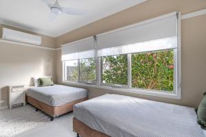 阿勒达拉Fish Cottage Ulladulla - Linen not supplied - 3 bedroom house - sleeps 8 - pet friendly的一间有两张床和一扇大窗户的卧室