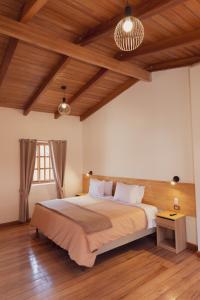a bedroom with a large bed and wooden ceilings at Casa Alba Ollantaytambo in Ollantaytambo