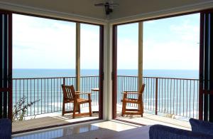 a room with a balcony with two chairs and a table at Castaways Resort in Waiuku