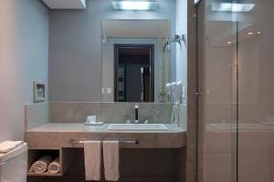 uma casa de banho com um lavatório e um espelho em Master Grande Hotel - Centro Histórico em Porto Alegre