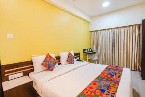 Un dormitorio con una cama grande y una pared amarilla. en FabHotel Sky View Palace - Marathahalli Outer Ring Road, en Bangalore