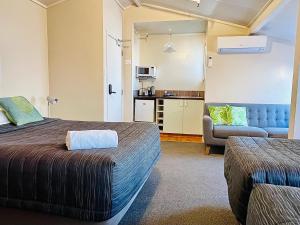a hotel room with two beds and a couch at Seagulls Guesthouse in Mount Maunganui