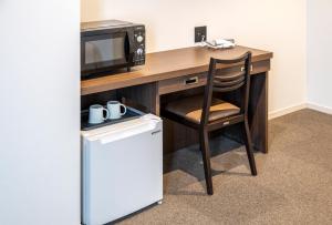 a computer desk with a microwave and a chair at TapStay Hotel in Saga