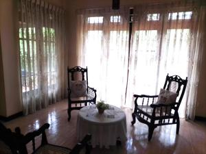 a living room with a table and chairs and windows at Fairland Bungalow in Kandy