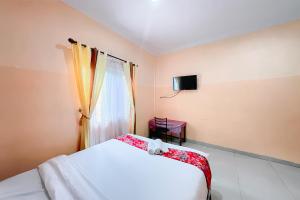 a bedroom with a white bed and a window at Hotel New Dieng By Helocus in Berastagi