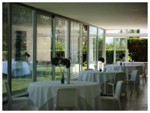 a room with white tables and chairs and windows at Hotel Villa San Bartolo in Vittoria