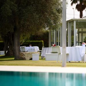 a table with white tables and chairs in front of a building at Hotel Villa San Bartolo in Vittoria