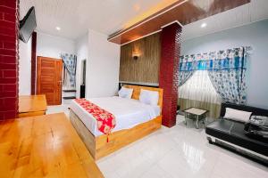 a bedroom with a bed and a couch at Hotel New Dieng By Helocus in Berastagi
