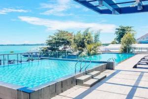 a large swimming pool next to a body of water at One Residence Apartment Batam in Batam Center