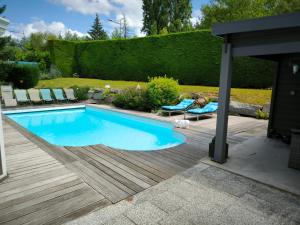 a swimming pool in a garden with a person laying on a chair next to it at Vro in Brunstatt