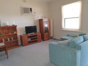 a living room with a blue couch and a tv at Sun on the Stubble in Maitland