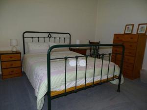 a bedroom with a bed with a metal frame and a dresser at Sun on the Stubble in Maitland
