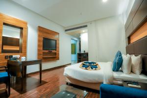 een slaapkamer met een bed, een bureau en een televisie bij Bel-La Monde Hotel Chhattarpur South Delhi in Sat Bari