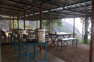 a pavilion with tables and benches with a mountain in the background at Campper Campwoody Munnar in Munnar