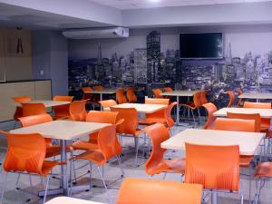 a cafeteria with tables and chairs and a tv on the wall at Hotel Urbainn in Veracruz