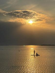 a couple of people standing on a paddle board in the water at Beach house with sauna in Hanko +1 photo