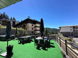 a patio with tables and umbrellas on a green lawn at Pamporovo Rhodopi Pearl Apartments - Private Apartments in Pamporovo