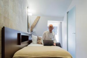 a man sitting on a bed using a laptop at Hotel The Century in Hasselt
