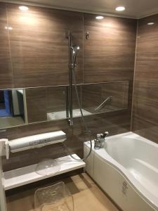 a bathroom with a shower and a tub and a sink at KKR Hotel Kumamoto in Kumamoto