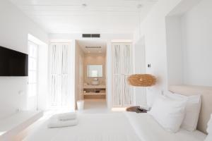 a white room with a bed and a television at The Ammonite Resort in Super Paradise Beach