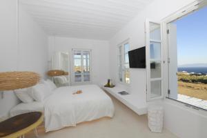 a white bedroom with a bed and a window at The Ammonite Resort in Super Paradise Beach