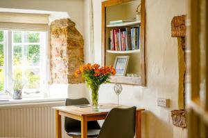eine Vase mit Blumen auf einem Tisch in einem Zimmer in der Unterkunft The Hangmans Cottage in Abbotskerswell