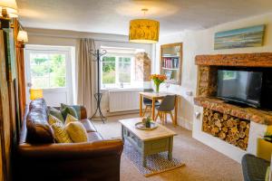 ein Wohnzimmer mit Couch und Kamin in der Unterkunft The Hangmans Cottage in Abbotskerswell