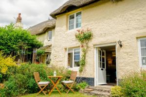 ein Häuschen mit einem Tisch und Stühlen davor in der Unterkunft The Hangmans Cottage in Abbotskerswell