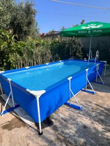 a blue swimming pool with a green umbrella at Holiday Home in Vlorë