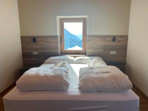 a bed with two pillows on it with a window at El Rocol in Ledro