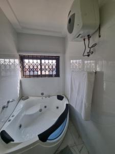 a white bathroom with a bath tub and a window at D11 New Oak in Accra +10 photos