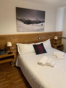 a bedroom with a white bed with two towels on it at Hotel Coeur Du Village in La Thuile