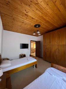 a bedroom with two beds and a flat screen tv at Armando's wooden roof in Berat
