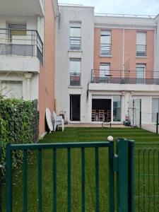 a fence in front of a yard with a house at Maison 5 pièces jardin in Aubervilliers
