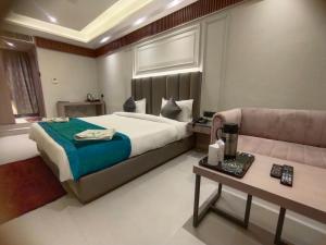 a bedroom with a large bed and a couch at Hotel Gagan Suite in Kānpur