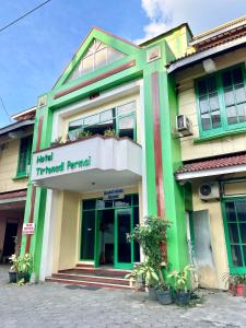 a green and yellow building with a sign on it at Hotel Tirtonadi Permai in Kadiporo