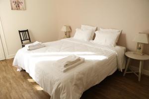 a white bed with white sheets and towels on it at Chablis Appart in Chablis