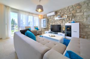 a living room with a couch and a tv at Villa Vinodol *with great sea view and pool in Novi Vinodolski