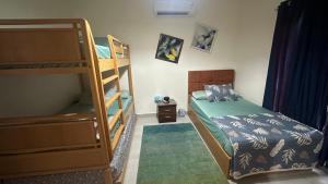a bedroom with two bunk beds and a bed with a green bedspread at Private chalet in Amwaj north coast 2 bed room and 2 bath امواج الساحل الشمالي شاليه غرفتين واتنين حمام مفروش ومكيف بالكامل in El Alamein +14 photos