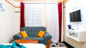 sala de estar con silla azul y almohadas de color naranja en Studio furnished Apartments Naivasha, en Naivasha