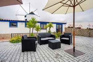 a patio with chairs and an umbrella and a house at Moinho das Esteveiras in A dos Cunhados