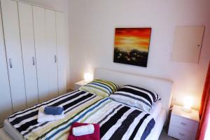 sypialnia z łóżkiem i obrazem na ścianie w obiekcie Apartmani Leonardo in Rabaca 36488 w Rabacu