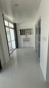 an empty room with white floors and large windows at Pinky's Beach House in Victoria