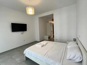 a white bedroom with a bed and a flat screen tv at Vibrant Omonia Oasis, Modern Apartment in the Heart of Athens in Athens