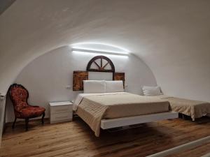 a white bedroom with a bed and a chair at Palazzo Grandori Alloggi Turistici in Viterbo
