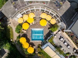 an overhead view of a pool with tables and yellow umbrellas at Naturhotel Ortners Eschenhof in Bad Kleinkirchheim
