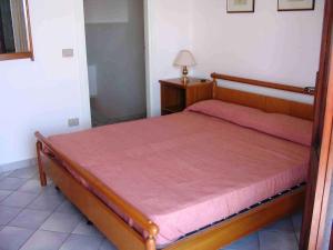 1 dormitorio con cama de madera y manta roja en Apartment Stintino - Insel Sardinien 23217, en Stintino