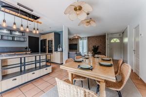 a kitchen and dining room with a wooden table and chairs at La Bohème du Lac - Maison climatisée avec piscine in La Teste-de-Buch +6 photos