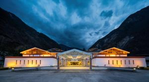 a building with mountains in the background at Lebanshan Hotel Jiuzhai Valley in Jiuzhaigou