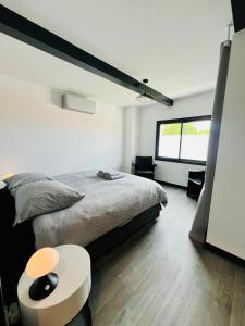 a white bedroom with a bed and a table at L'Escapade - Villa avec piscine in La Rochelle